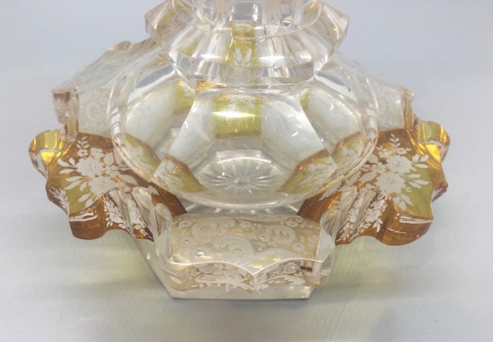 A Victorian cut crystal scent bottle with amber-stained floral engraving around the base, a faceted neck, and a tall pointed glass stopper. View IV