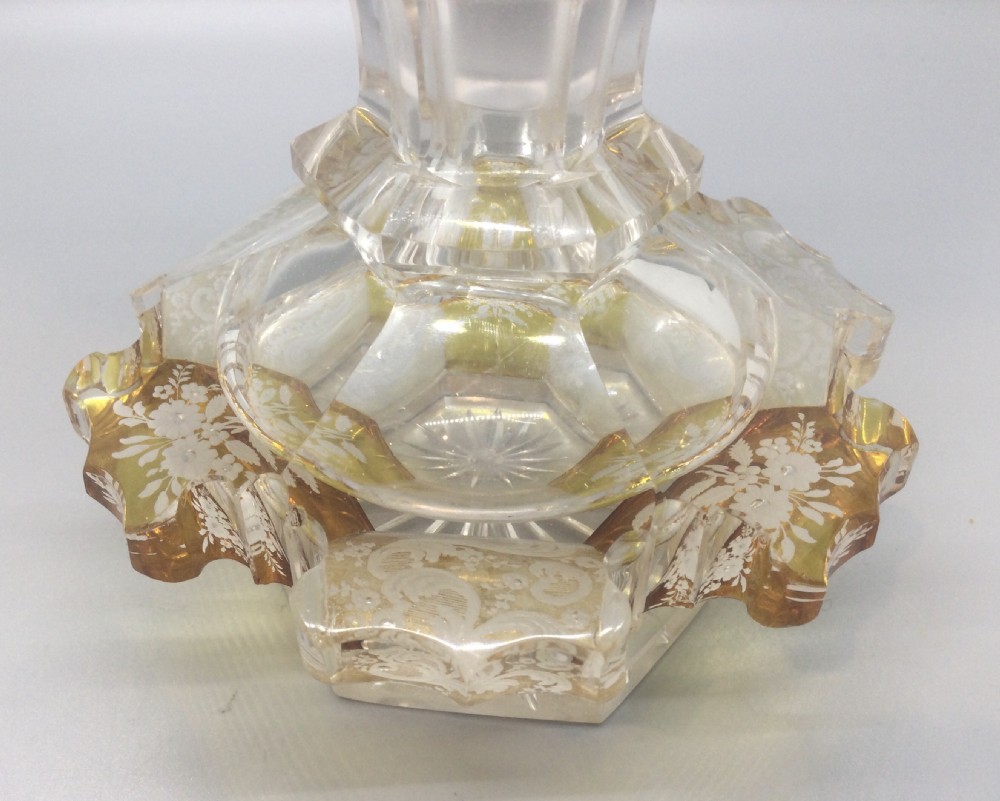 A Victorian cut crystal scent bottle with amber-stained floral engraving around the base, a faceted neck, and a tall pointed glass stopper. View V