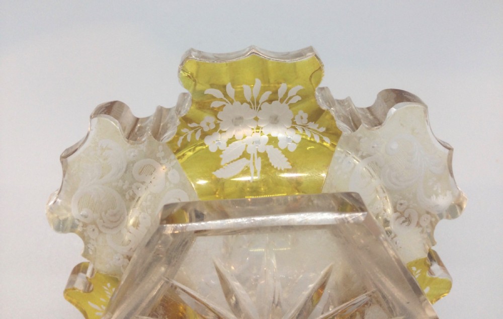 A Victorian cut crystal scent bottle with amber-stained floral engraving around the base, a faceted neck, and a tall pointed glass stopper. View XI