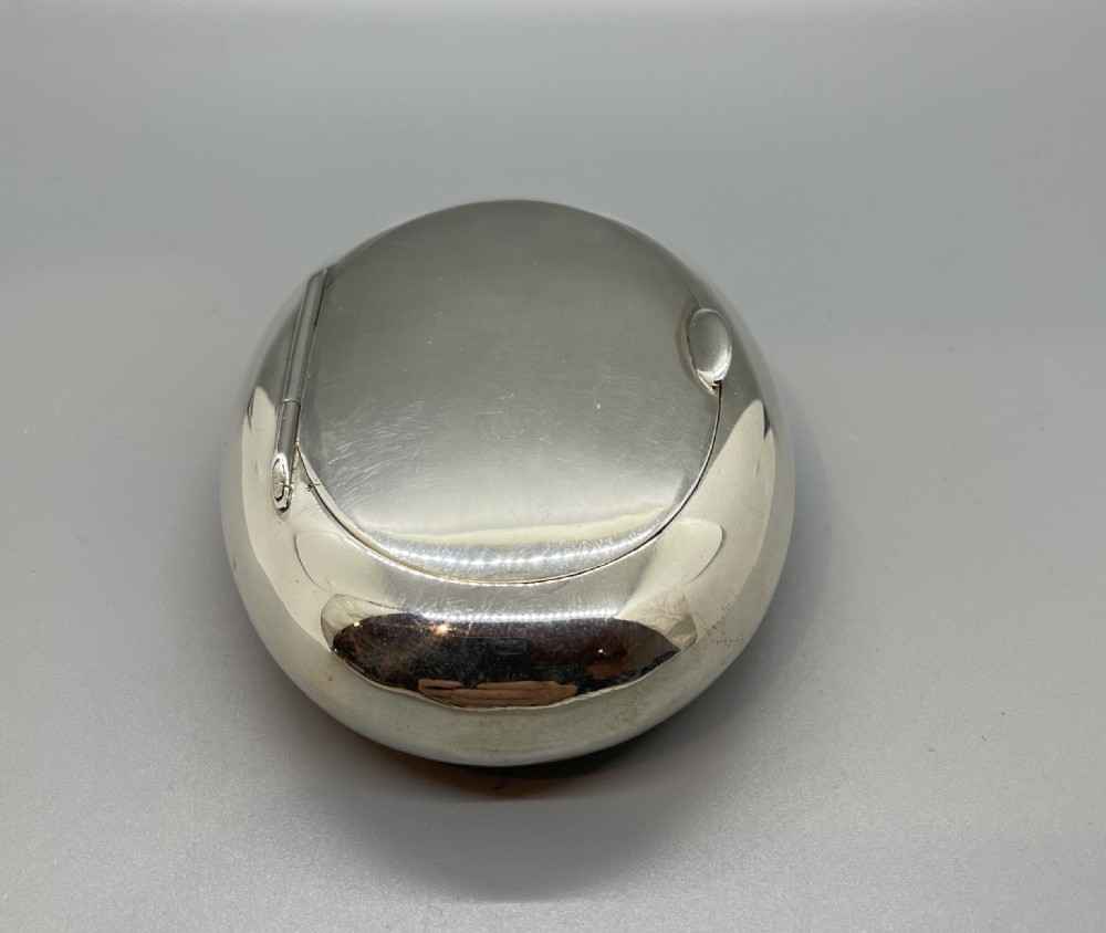 A smooth, oval sterling silver tobacco box with a polished finish and a hinged lid. View II