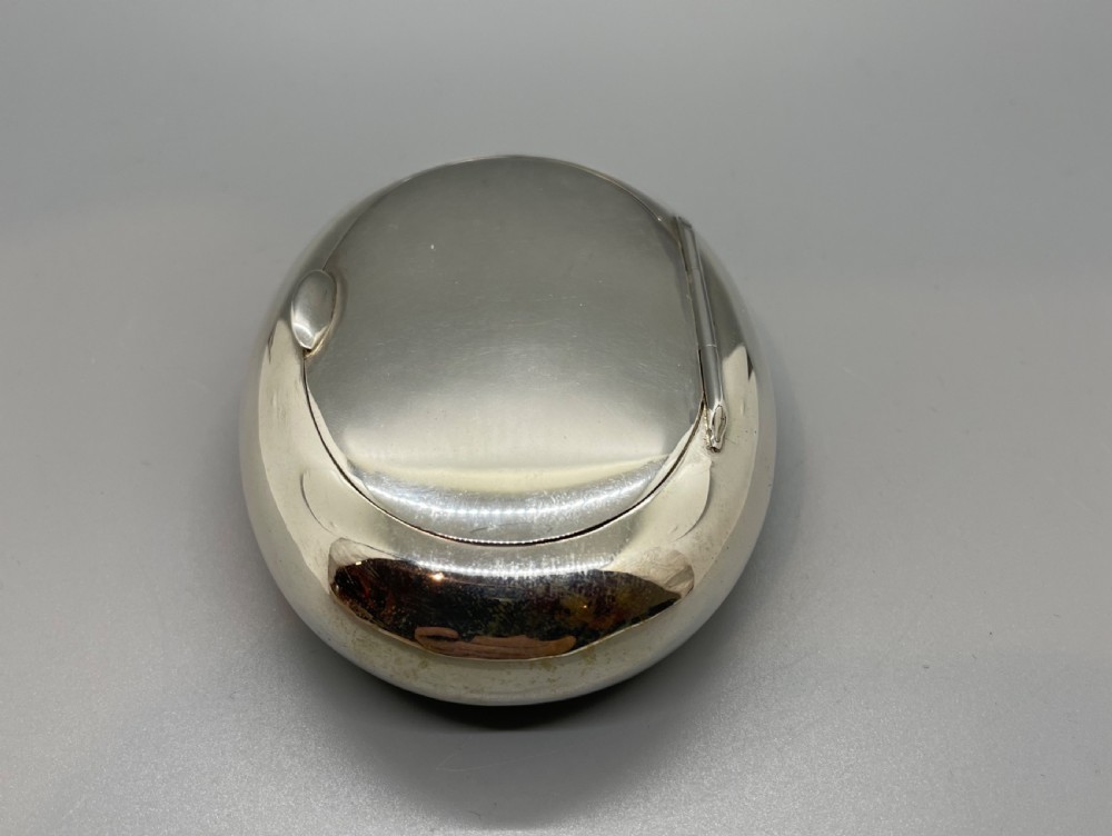 A smooth, oval sterling silver tobacco box with a polished finish and a hinged lid. View IV