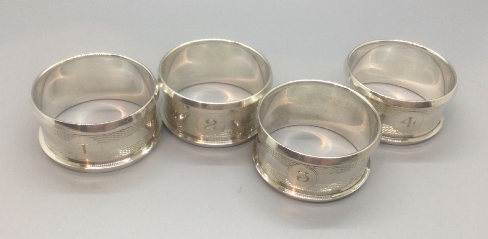 A set of four numbered sterling silver napkin rings featuring engine-turned decoration, presented in an open fitted leatherette box. View II