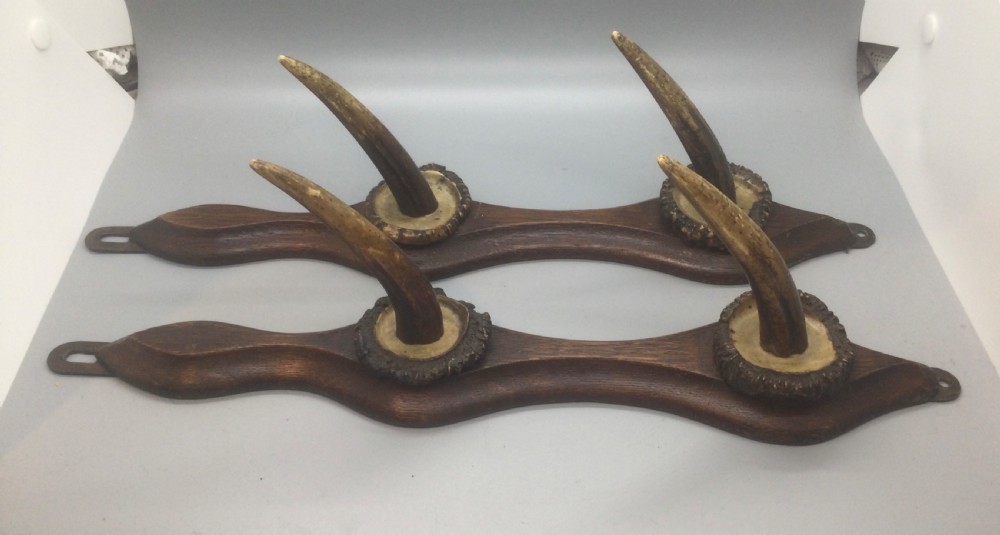 A pair of French turn-of-the-century wall-mounted coat hooks featuring shaped dark timber backplates and naturally textured horn tines. View V