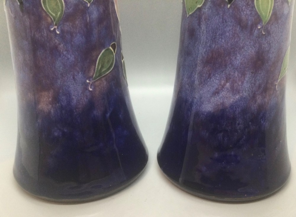 A matching pair of Royal Doulton Art Nouveau stoneware vases featuring stylized cream and soft pink rose motifs against a mottled cobalt blue background. View IX