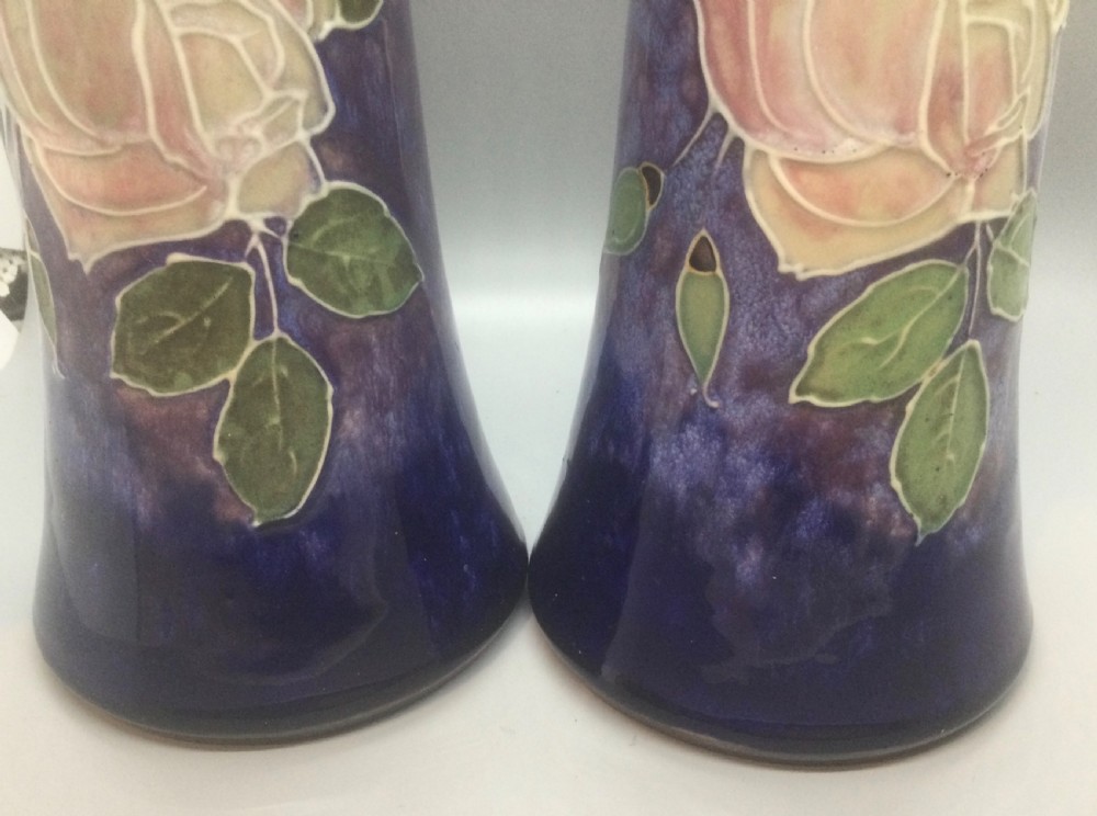 A matching pair of Royal Doulton Art Nouveau stoneware vases featuring stylized cream and soft pink rose motifs against a mottled cobalt blue background. View XII