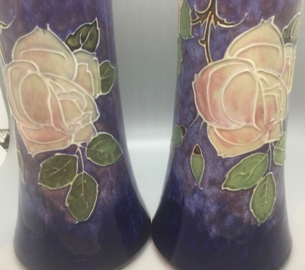 A matching pair of Royal Doulton Art Nouveau stoneware vases featuring stylized cream and soft pink rose motifs against a mottled cobalt blue background. View XIII