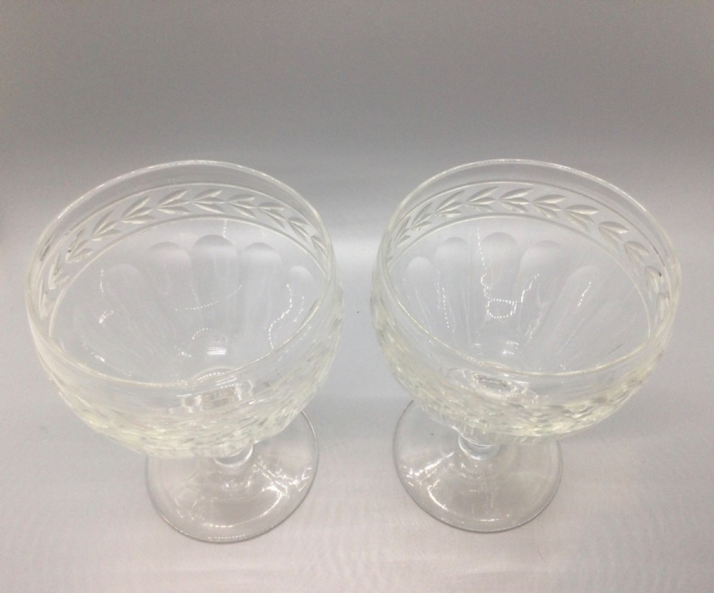 A pair of Edwardian clear cut lead crystal wine glasses with wheel-engraved leaf bands and vertical facet cuts. View II