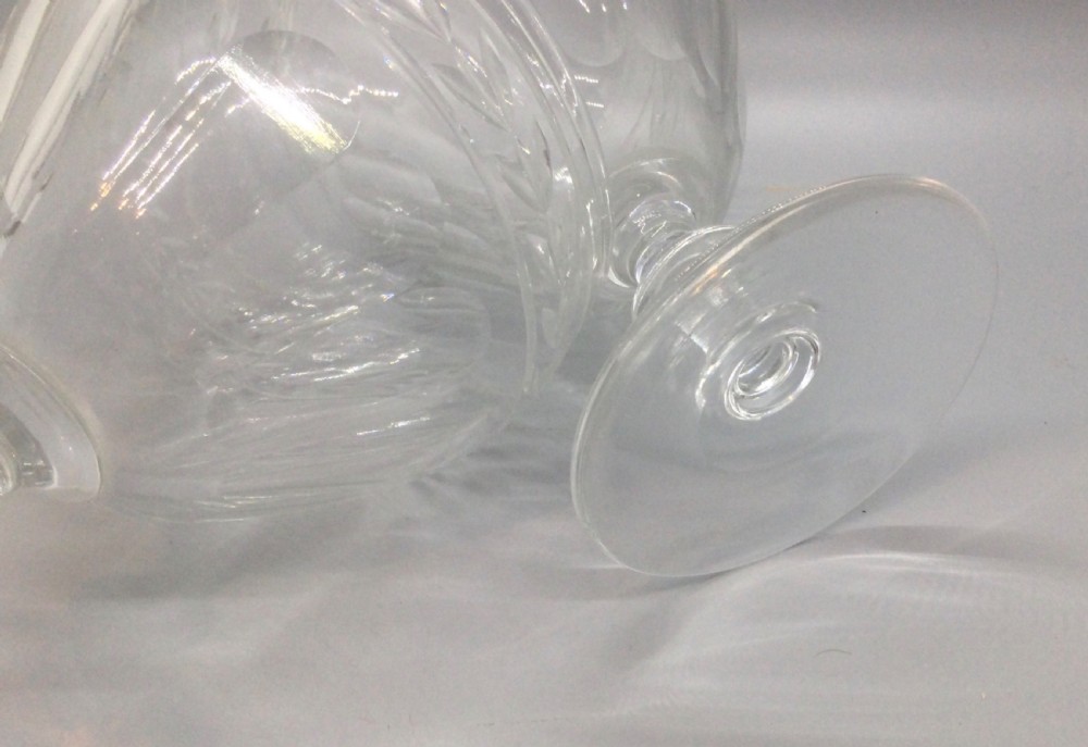 A pair of Edwardian clear cut lead crystal wine glasses with wheel-engraved leaf bands and vertical facet cuts. View IV