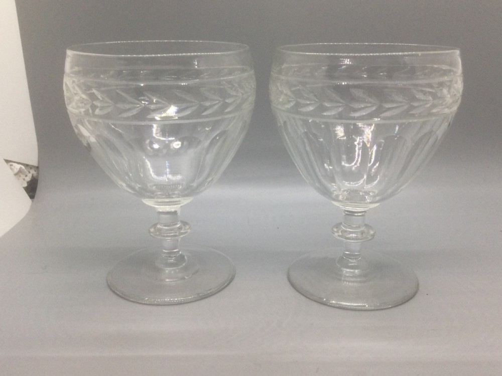 A pair of Edwardian clear cut lead crystal wine glasses with wheel-engraved leaf bands and vertical facet cuts. View X