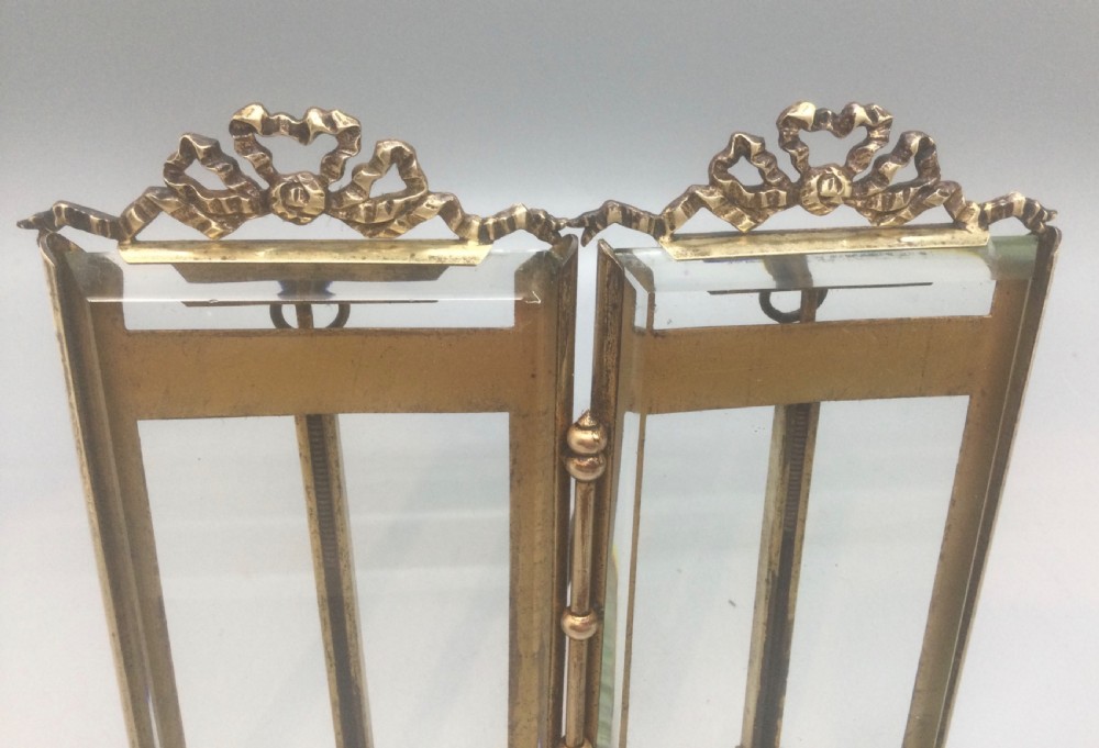 A late 19th-century French double photo frame made of gilt metal with ribbon cresting, bevelled glass, and ball feet. View VIII