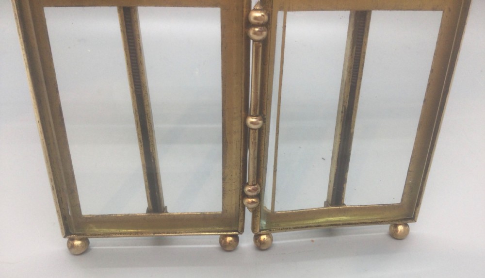 A late 19th-century French double photo frame made of gilt metal with ribbon cresting, bevelled glass, and ball feet. View IX
