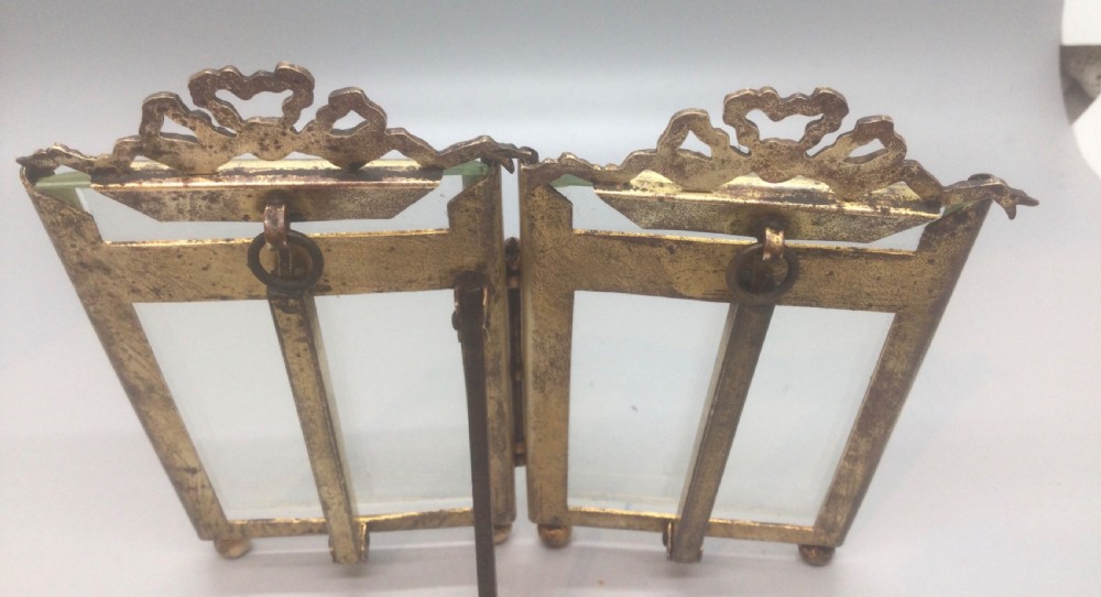 A late 19th-century French double photo frame made of gilt metal with ribbon cresting, bevelled glass, and ball feet. View X