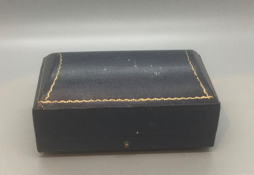 A pair of engine-turned sterling silver napkin rings with vacant oval cartouches, presented inside a blue velvet-lined fitted display case. View V
