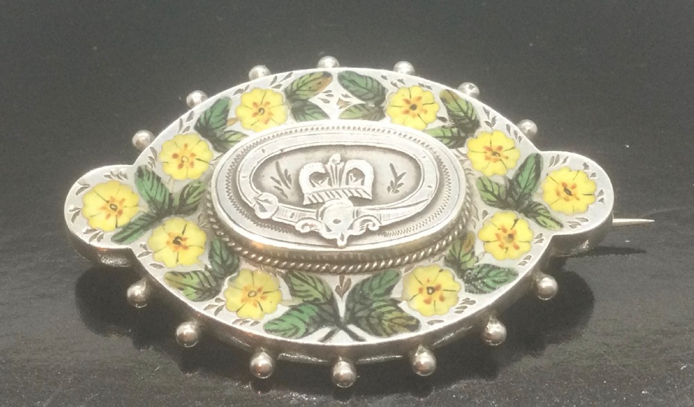 An oval Victorian silver brooch decorated with hand-painted yellow enamel flowers, green leaves, beaded outer edges, and a central silver crest motif. View III