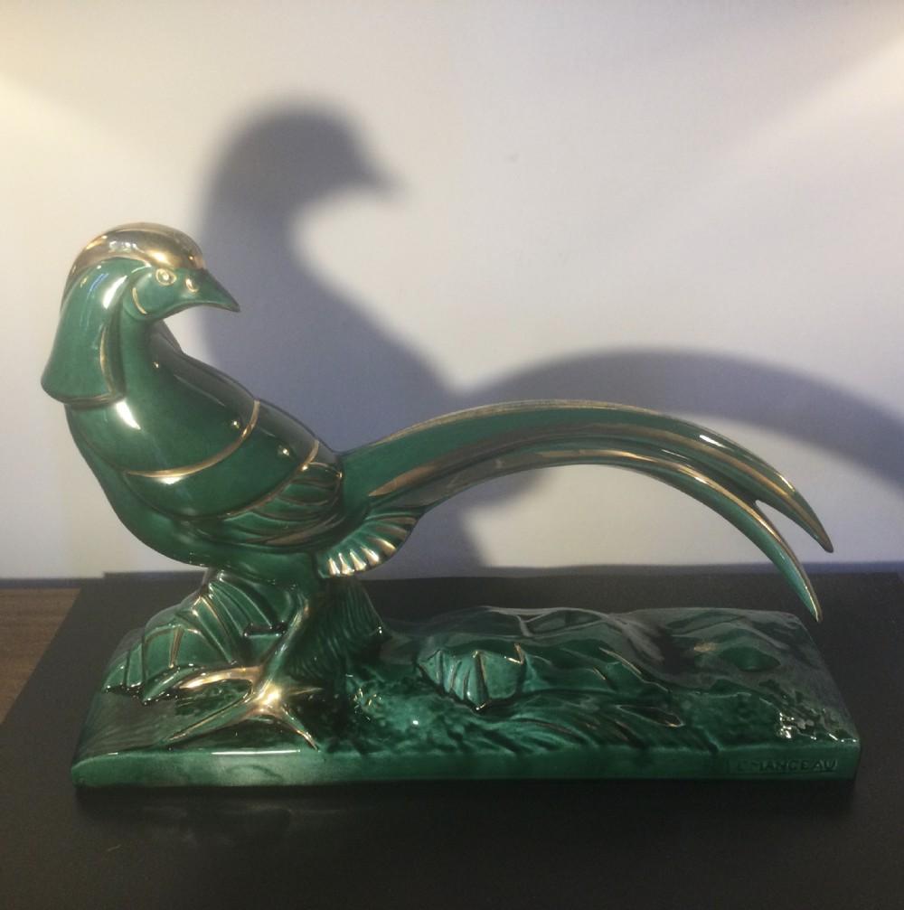 A stylised Art Deco green glazed ceramic pheasant figurine featuring fine gold line details and an extended sweeping tail resting on an integrated base.