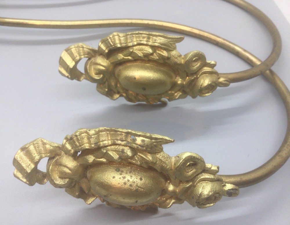 A pair of 19th-century French ormolu curtain tiebacks with long curved arms and ornamental floral backplates. View II
