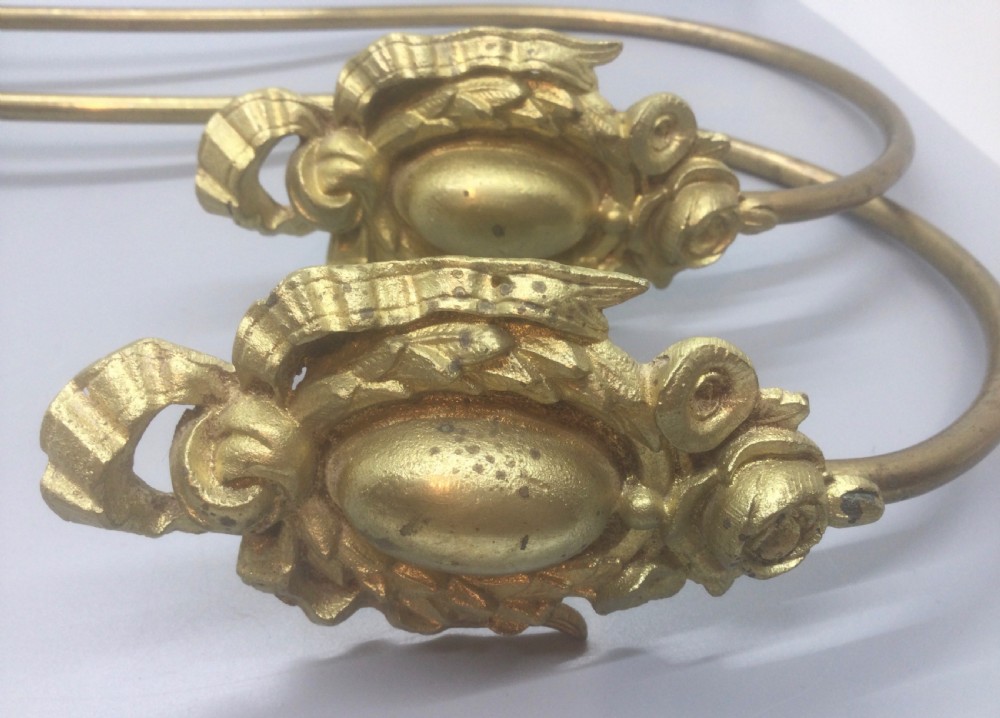 A pair of 19th-century French ormolu curtain tiebacks with long curved arms and ornamental floral backplates. View III