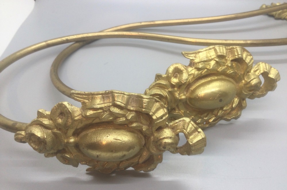 A pair of 19th-century French ormolu curtain tiebacks with long curved arms and ornamental floral backplates. View V