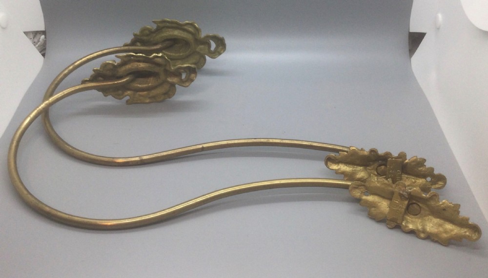 A pair of 19th-century French ormolu curtain tiebacks with long curved arms and ornamental floral backplates. View VI