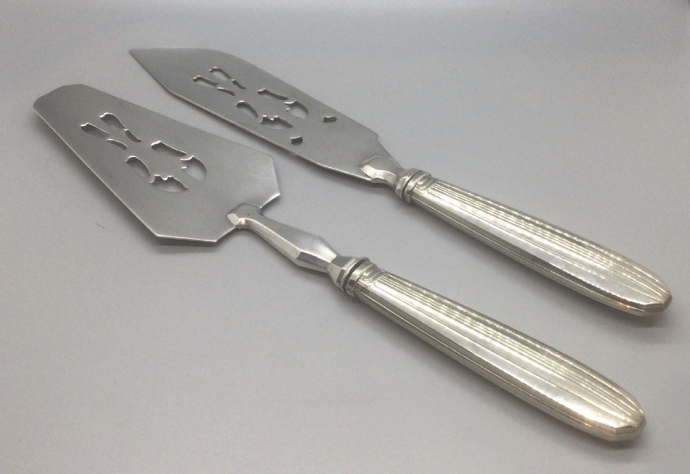 A pair of French silver-plated Art Deco cake servers with ribbed handles and pierced blades inside a white satin-lined presentation case. View IV