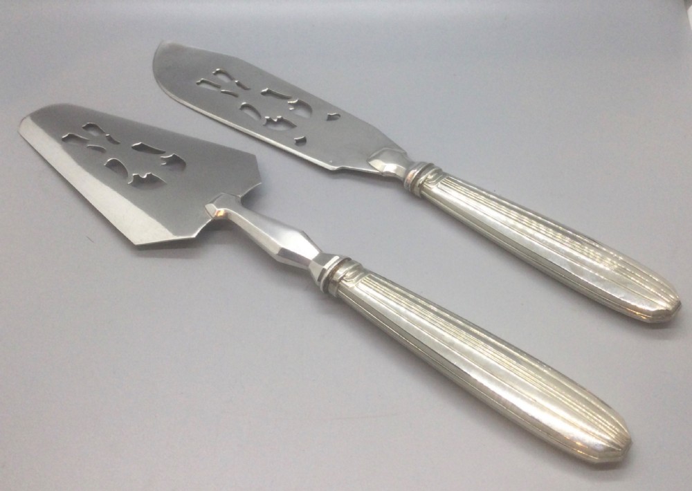 A pair of French silver-plated Art Deco cake servers with ribbed handles and pierced blades inside a white satin-lined presentation case. View V