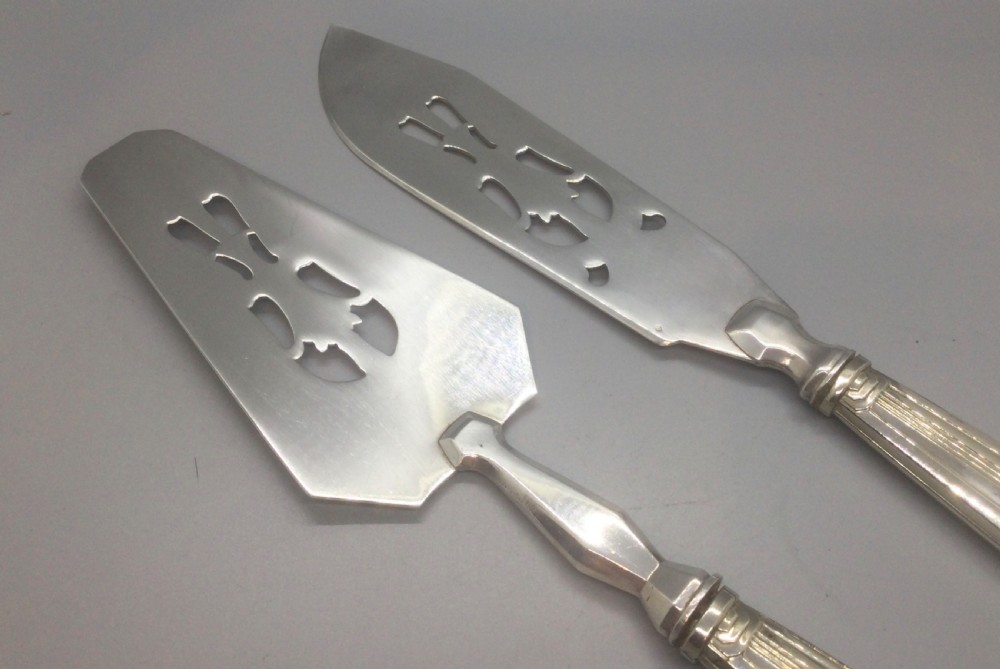 A pair of French silver-plated Art Deco cake servers with ribbed handles and pierced blades inside a white satin-lined presentation case. View VI