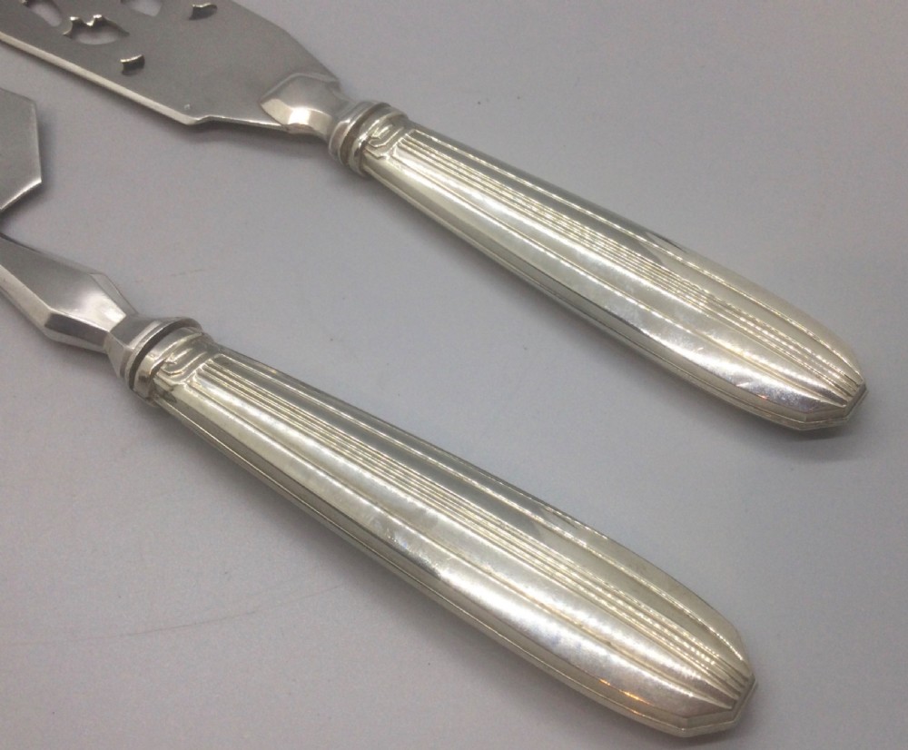 A pair of French silver-plated Art Deco cake servers with ribbed handles and pierced blades inside a white satin-lined presentation case. View VII