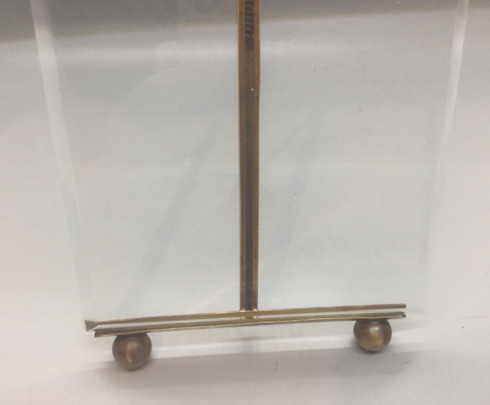 A late 19th-century French easel photo frame featuring thick bevelled glass, a ribbon bow top motif, spherical feet, and a gilded bronze framework. View IV