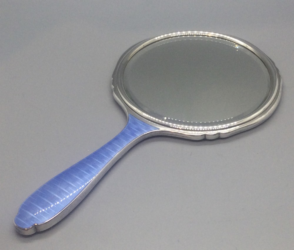 An Art Deco sterling silver hand mirror featuring a vibrant blue guilloche enamel back with a sunburst engine-turned motif. View V