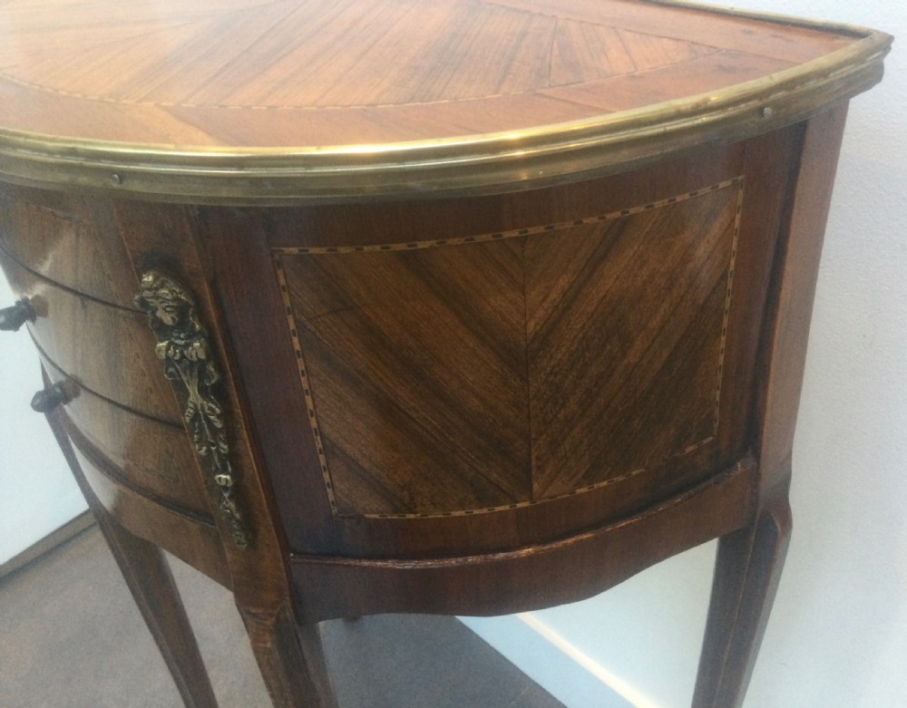 A late 19th-century French kingwood demi-lune console table featuring three drawers with geometric parquetry veneer, brass mounts, and long cabriole legs. View III