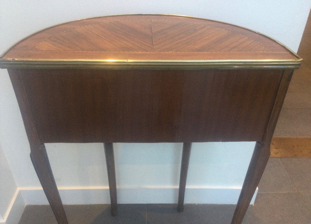 A late 19th-century French kingwood demi-lune console table featuring three drawers with geometric parquetry veneer, brass mounts, and long cabriole legs. View V
