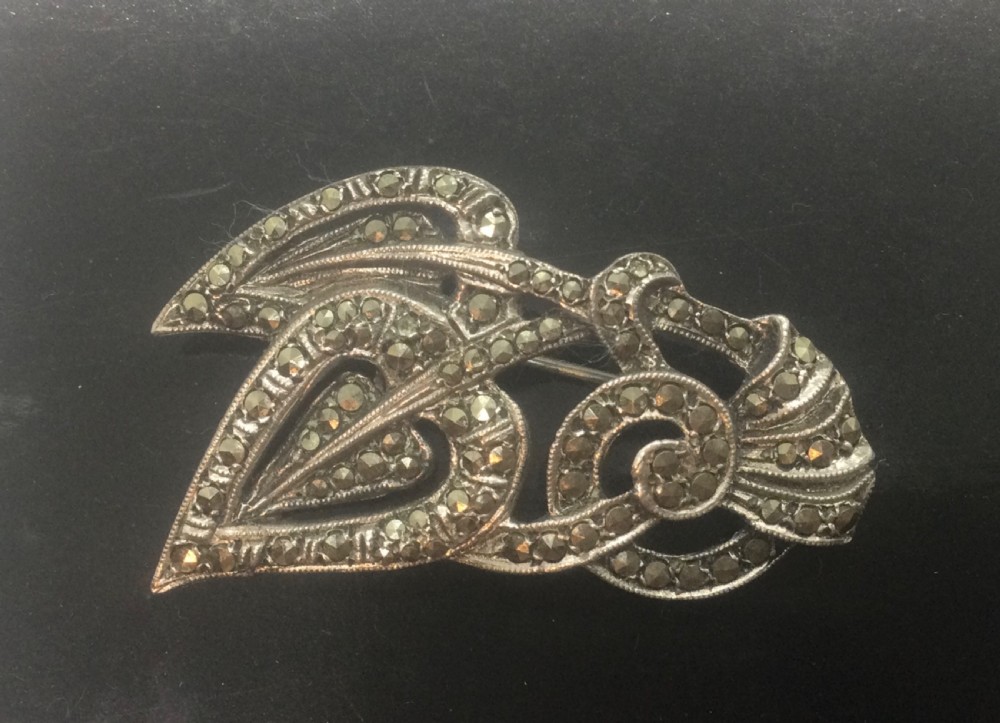 An Art Deco silver marcasite brooch featuring two stylised overlapping hearts connected with swirling ribbon motifs. View II