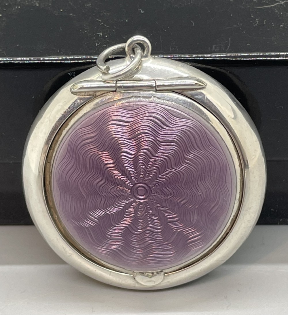 A circular sterling silver compact pendant featuring a purple guilloche enamel panel with a wavy engine-turned pattern and a top hanging ring.