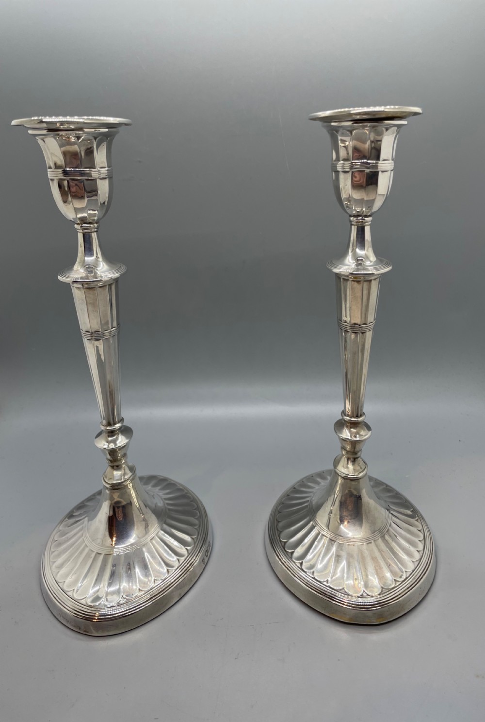 A pair of Victorian sterling silver candlesticks featuring fluted tapered shafts, sconces with reeded rims, and circular lobed bases. View II