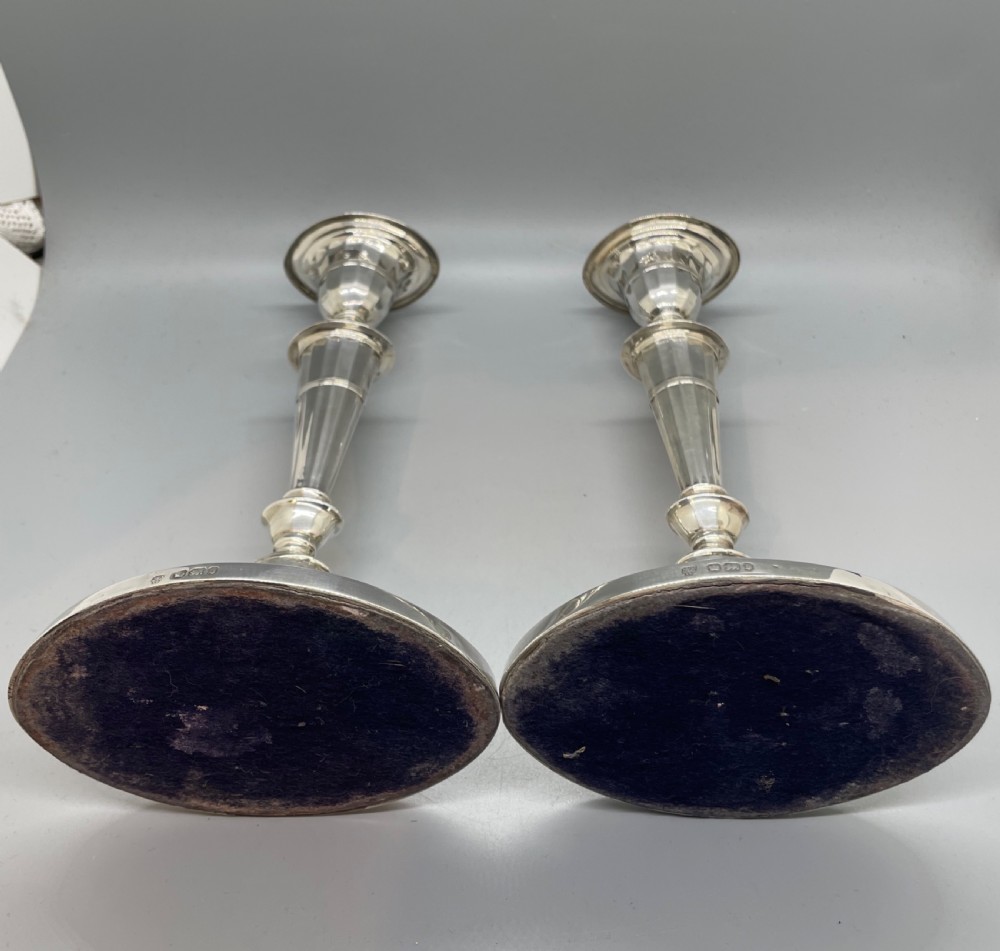 A pair of Victorian sterling silver candlesticks featuring fluted tapered shafts, sconces with reeded rims, and circular lobed bases. View V