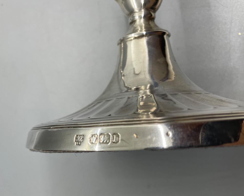A pair of Victorian sterling silver candlesticks featuring fluted tapered shafts, sconces with reeded rims, and circular lobed bases. View VI
