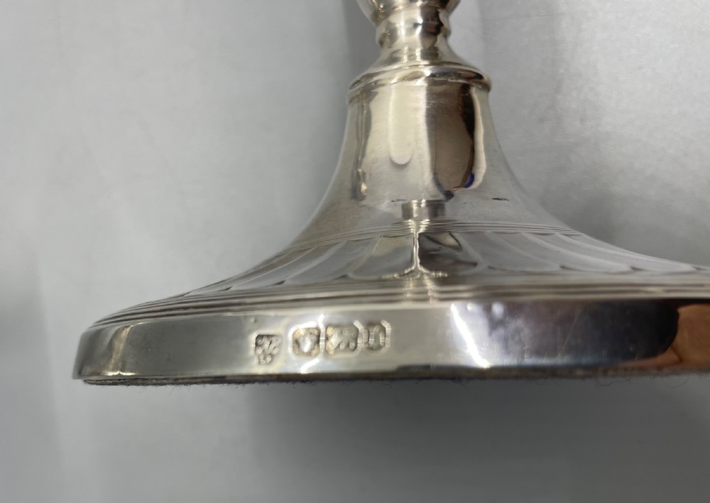 A pair of Victorian sterling silver candlesticks featuring fluted tapered shafts, sconces with reeded rims, and circular lobed bases. View VII
