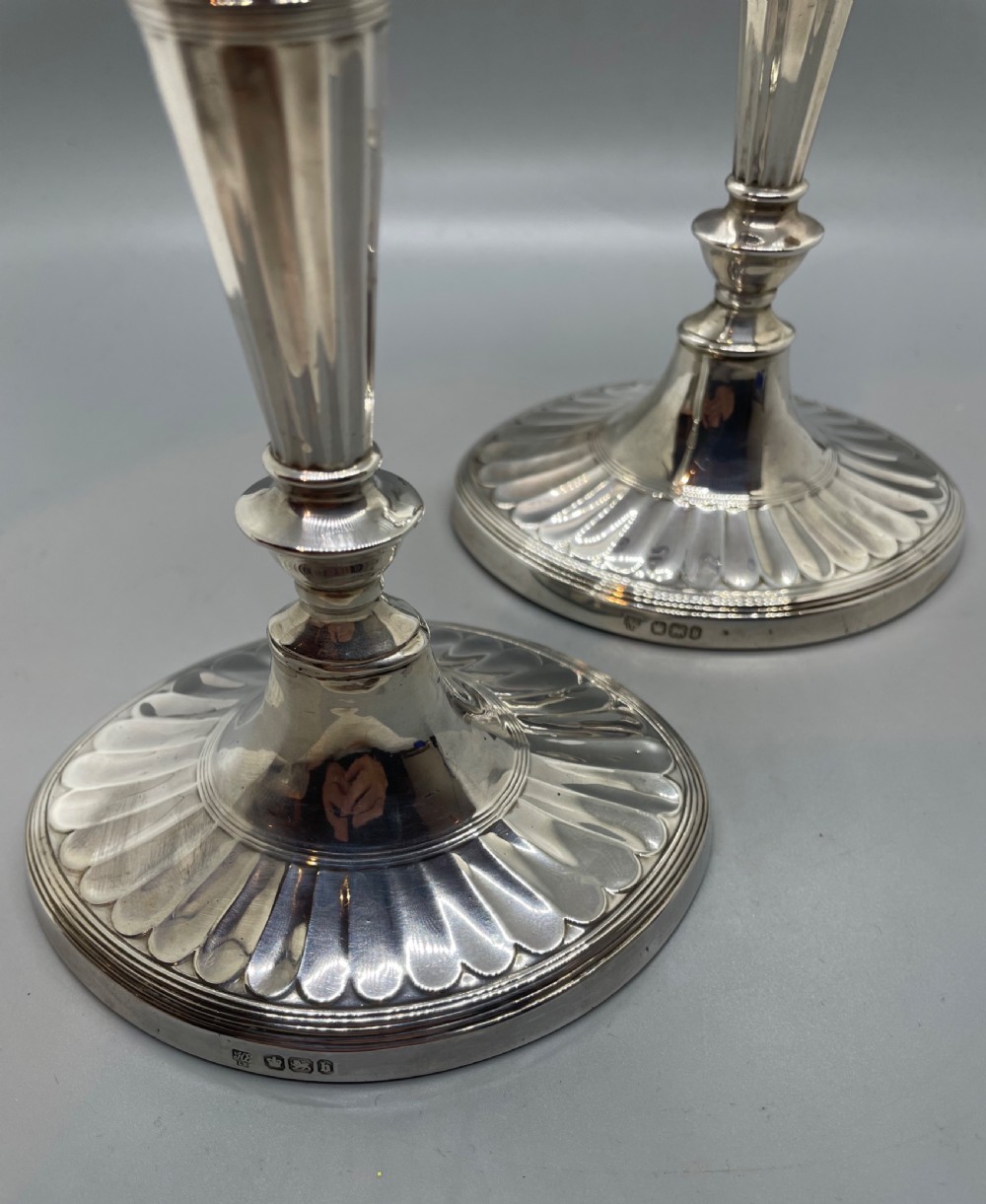 A pair of Victorian sterling silver candlesticks featuring fluted tapered shafts, sconces with reeded rims, and circular lobed bases. View VIII
