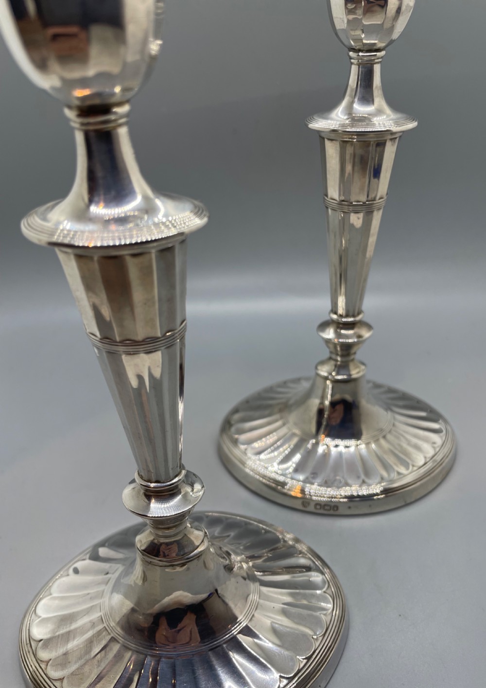 A pair of Victorian sterling silver candlesticks featuring fluted tapered shafts, sconces with reeded rims, and circular lobed bases. View X