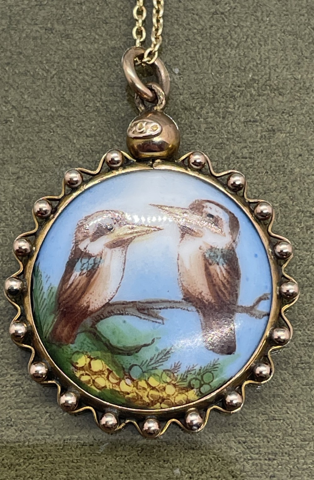 A circular late 19th-century 9ct gold pendant featuring a hand-painted enamel depiction of two kookaburras perched on a branch within a beaded border. View II