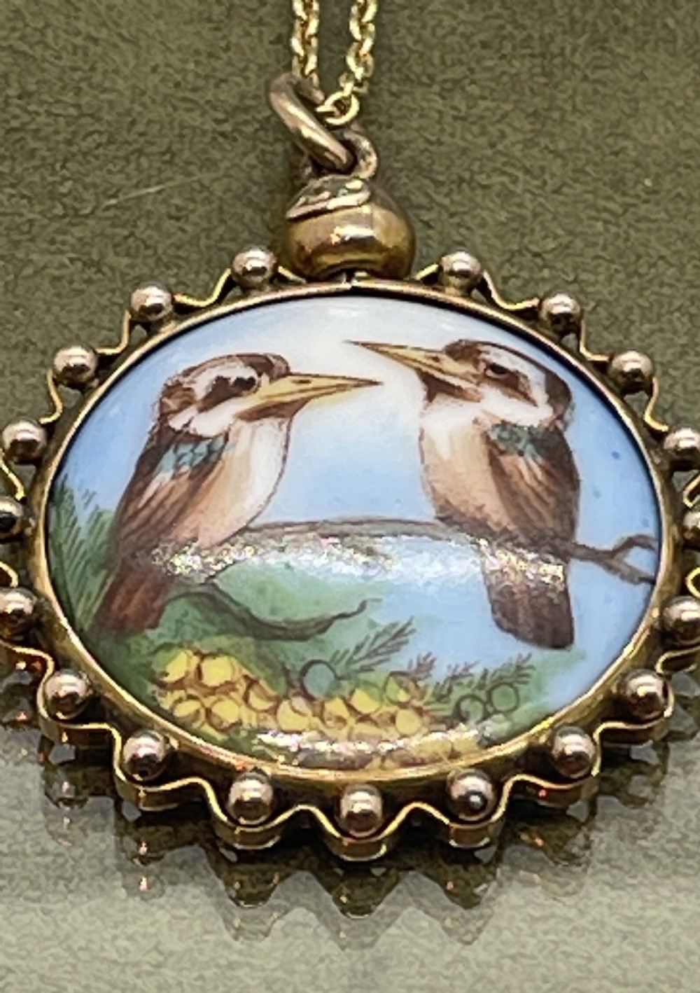 A circular late 19th-century 9ct gold pendant featuring a hand-painted enamel depiction of two kookaburras perched on a branch within a beaded border. View VI