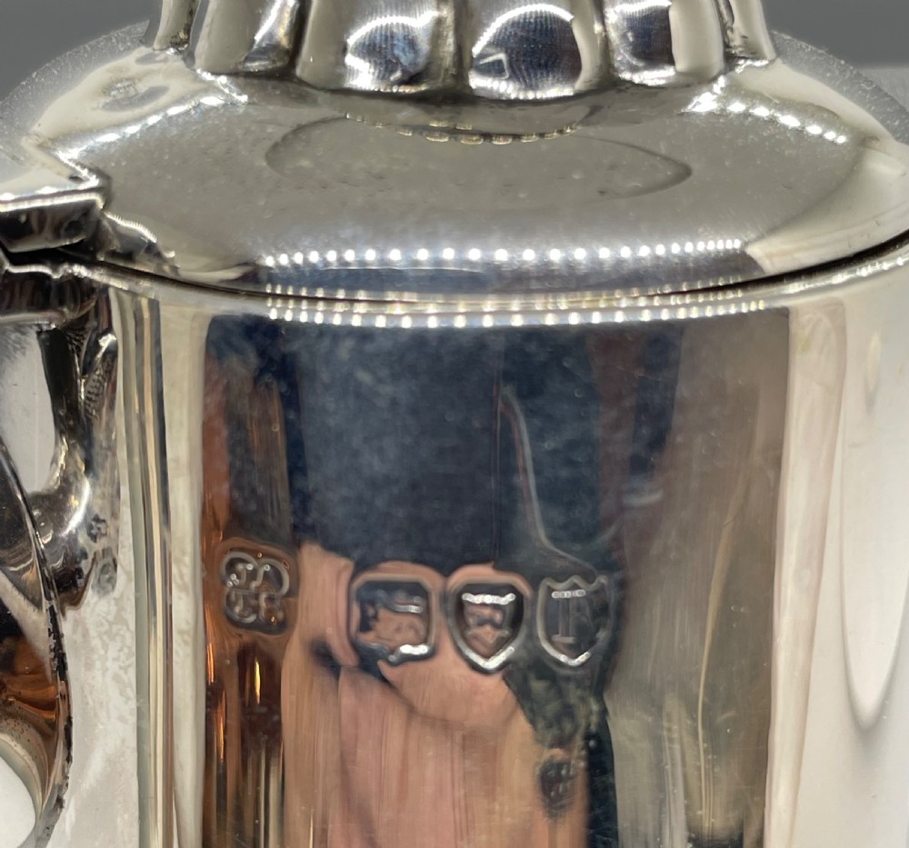 A late Victorian cut-crystal claret jug featuring a fluted glass body, hallmarked sterling silver mounts, a hinged lid, and an angular handle. View IV