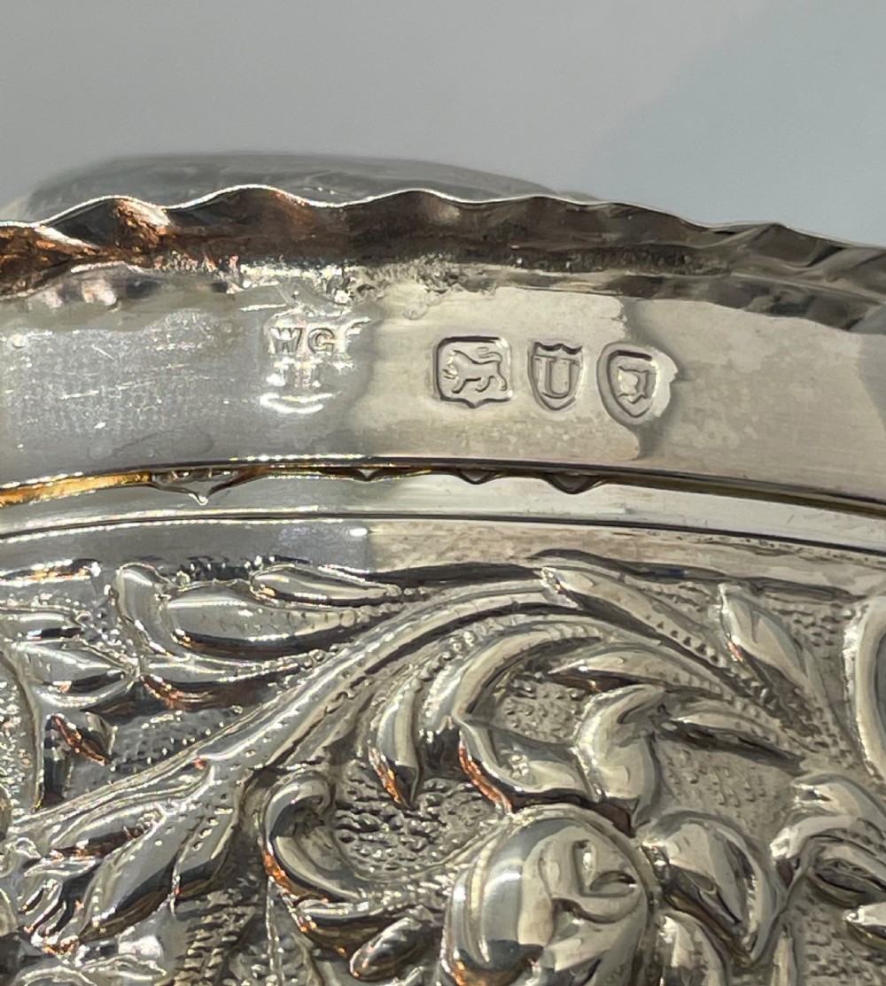 A heart-shaped sterling silver trinket box decorated with relief foliate scrollwork, a crimped rim, and a smooth central cartouche. View VIII