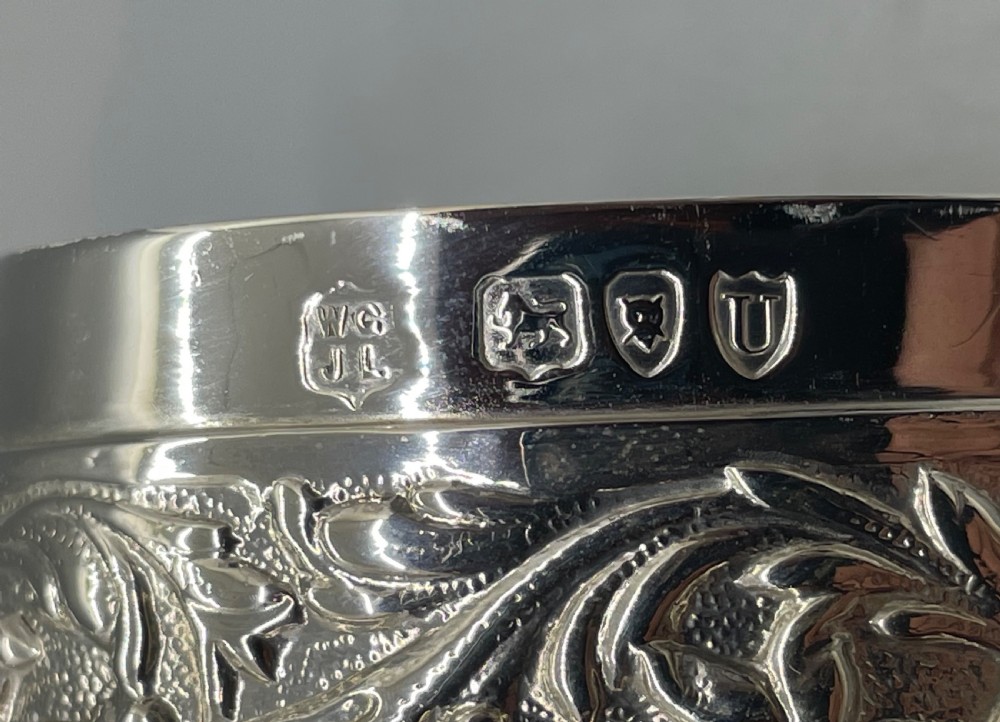 A heart-shaped sterling silver trinket box decorated with relief foliate scrollwork, a crimped rim, and a smooth central cartouche. View IX