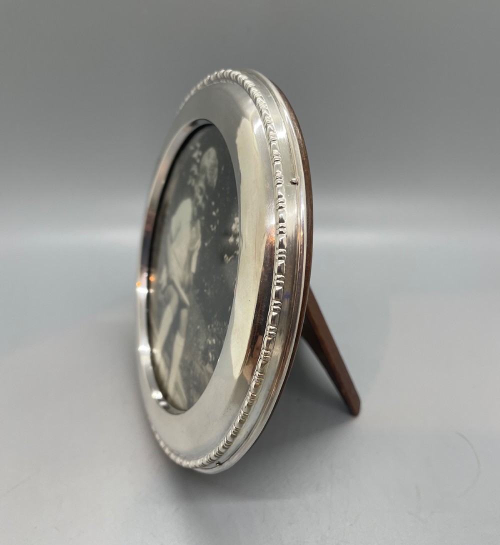 A circular George V sterling silver picture frame featuring a beaded outer rim, displaying a black and white photograph of a young boy. View III