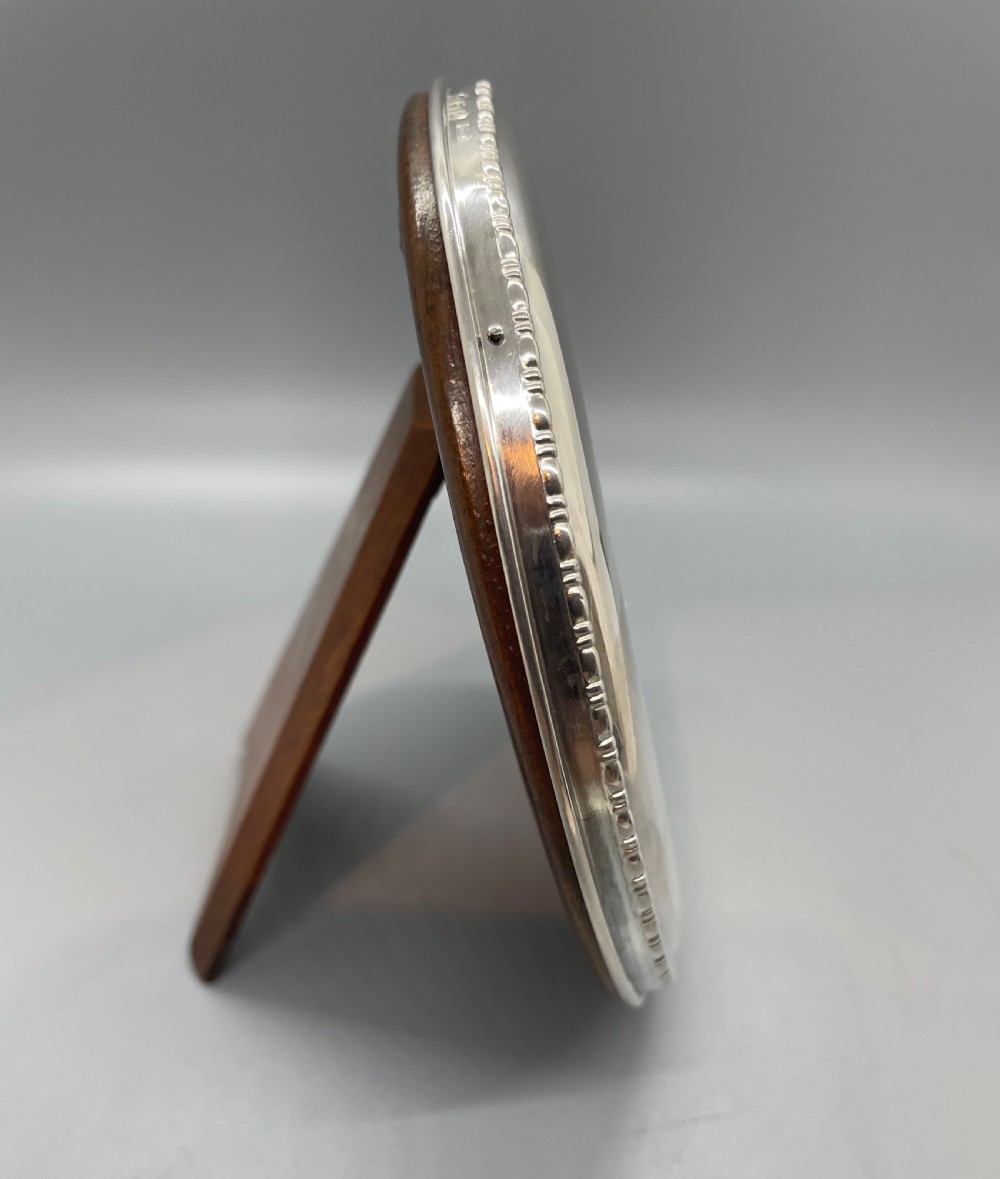 A circular George V sterling silver picture frame featuring a beaded outer rim, displaying a black and white photograph of a young boy. View VI