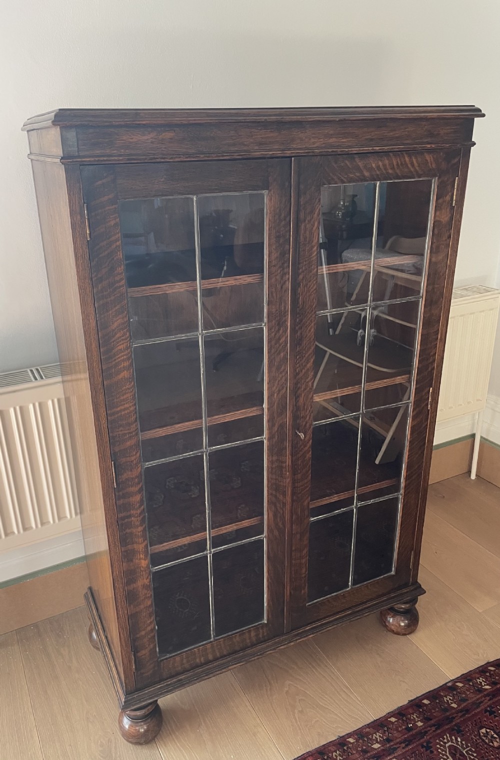 A 1920s dark oak bookcase featuring twin glazed doors with leaded glass panes, set on turned bun feet. View II