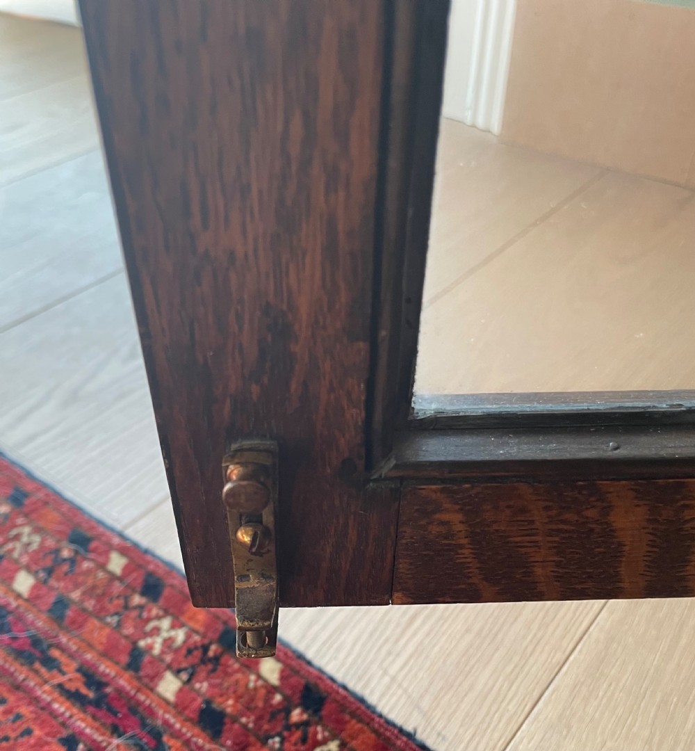 A 1920s dark oak bookcase featuring twin glazed doors with leaded glass panes, set on turned bun feet. View IX