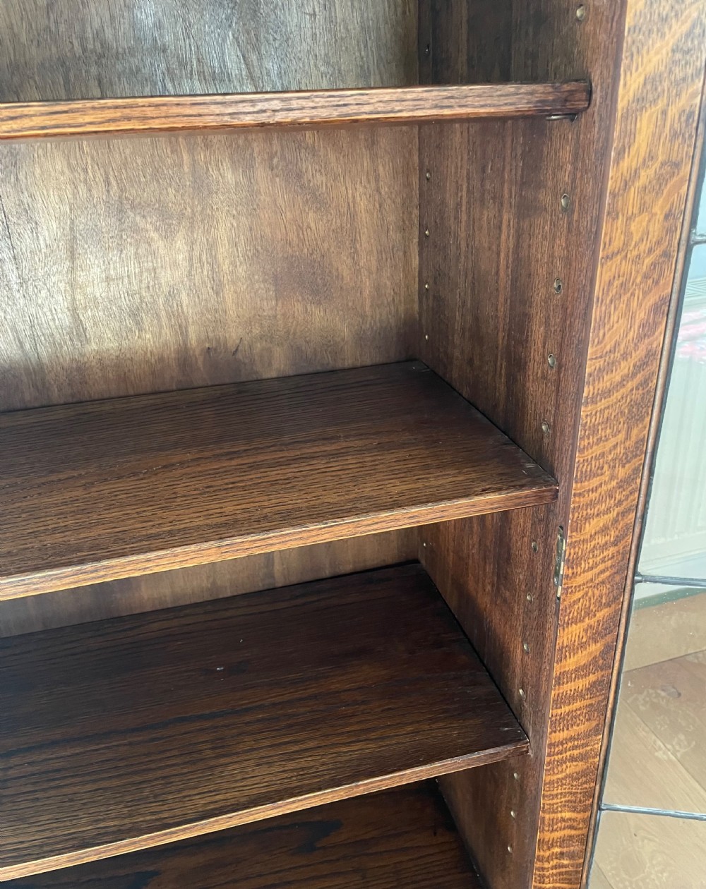 A 1920s dark oak bookcase featuring twin glazed doors with leaded glass panes, set on turned bun feet. View X