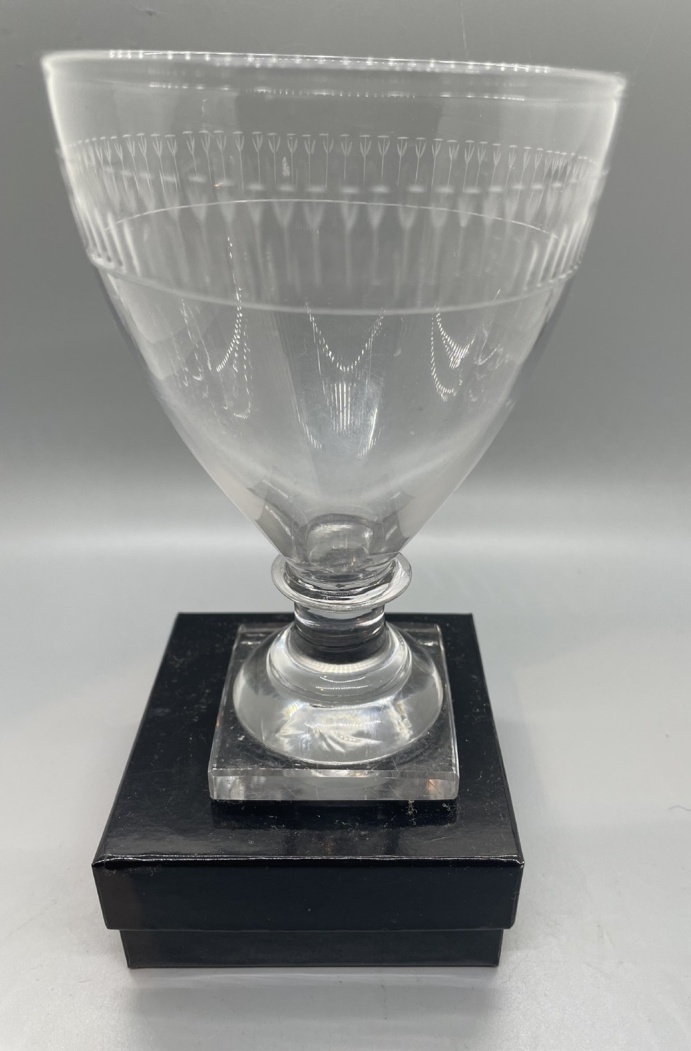 A clear Georgian glass rummer goblet featuring an etched rim band and a square pedestal base. View II